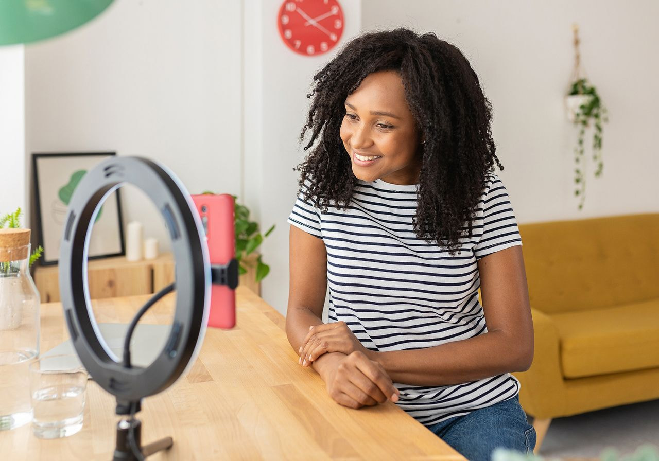 A social media influencer is recording herself using a mobile phone on a stand.